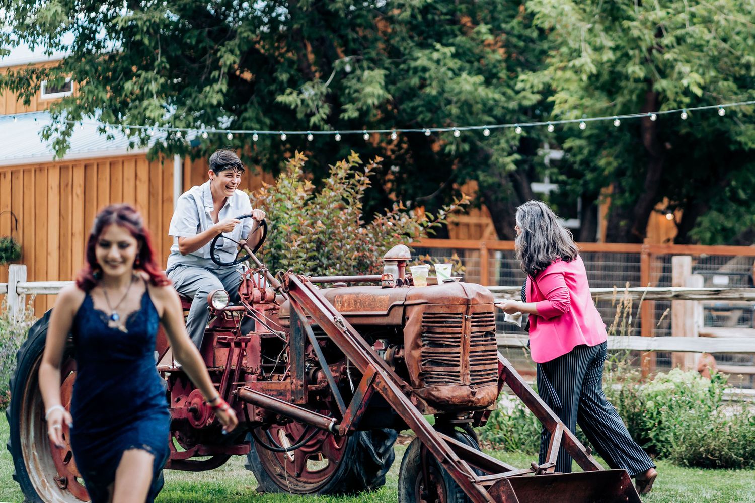 People interact around a vintage red farm equipment display in an outdoor venue setting.