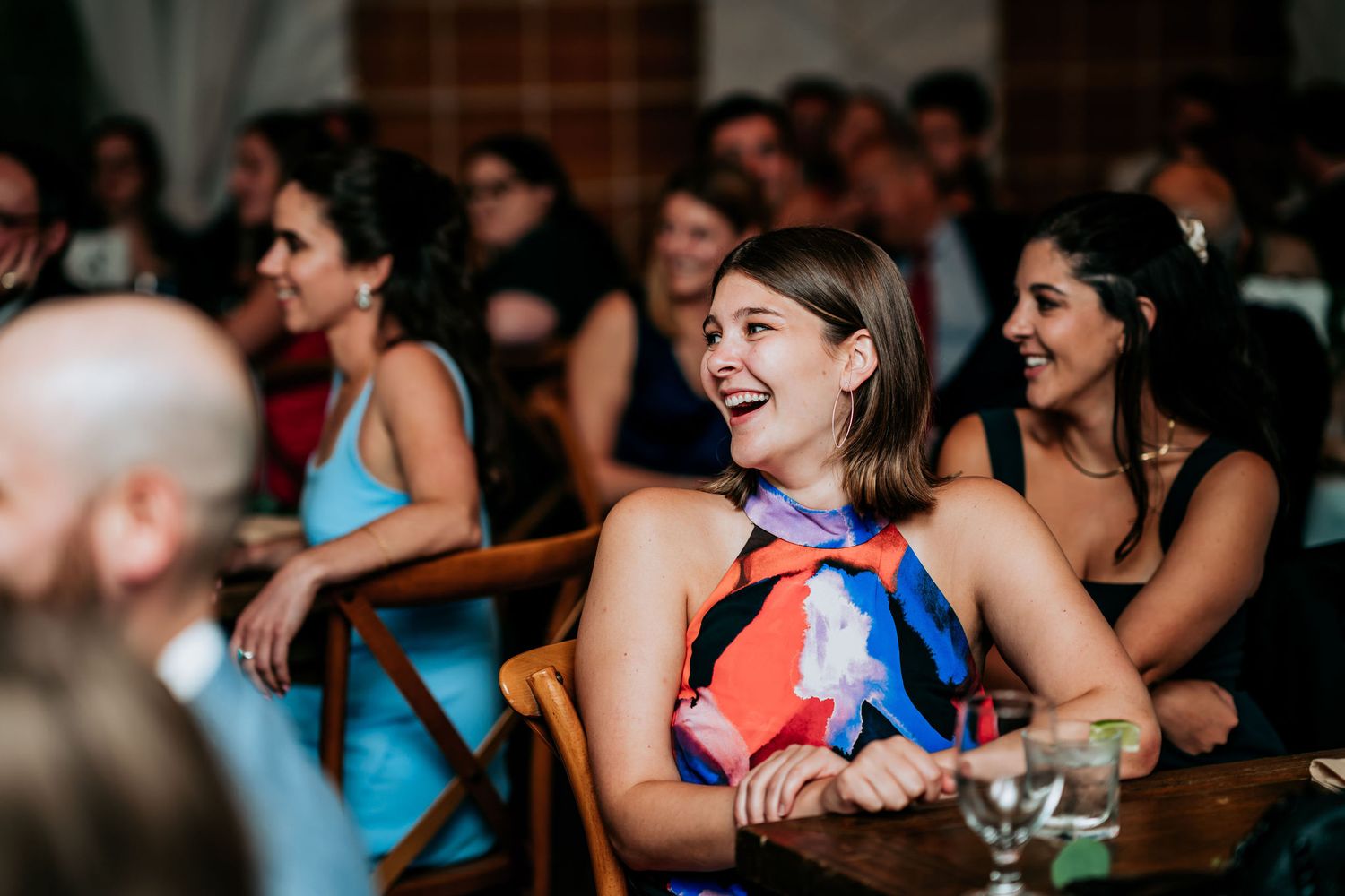 Wedding guests laugh and smile during a celebration reception.