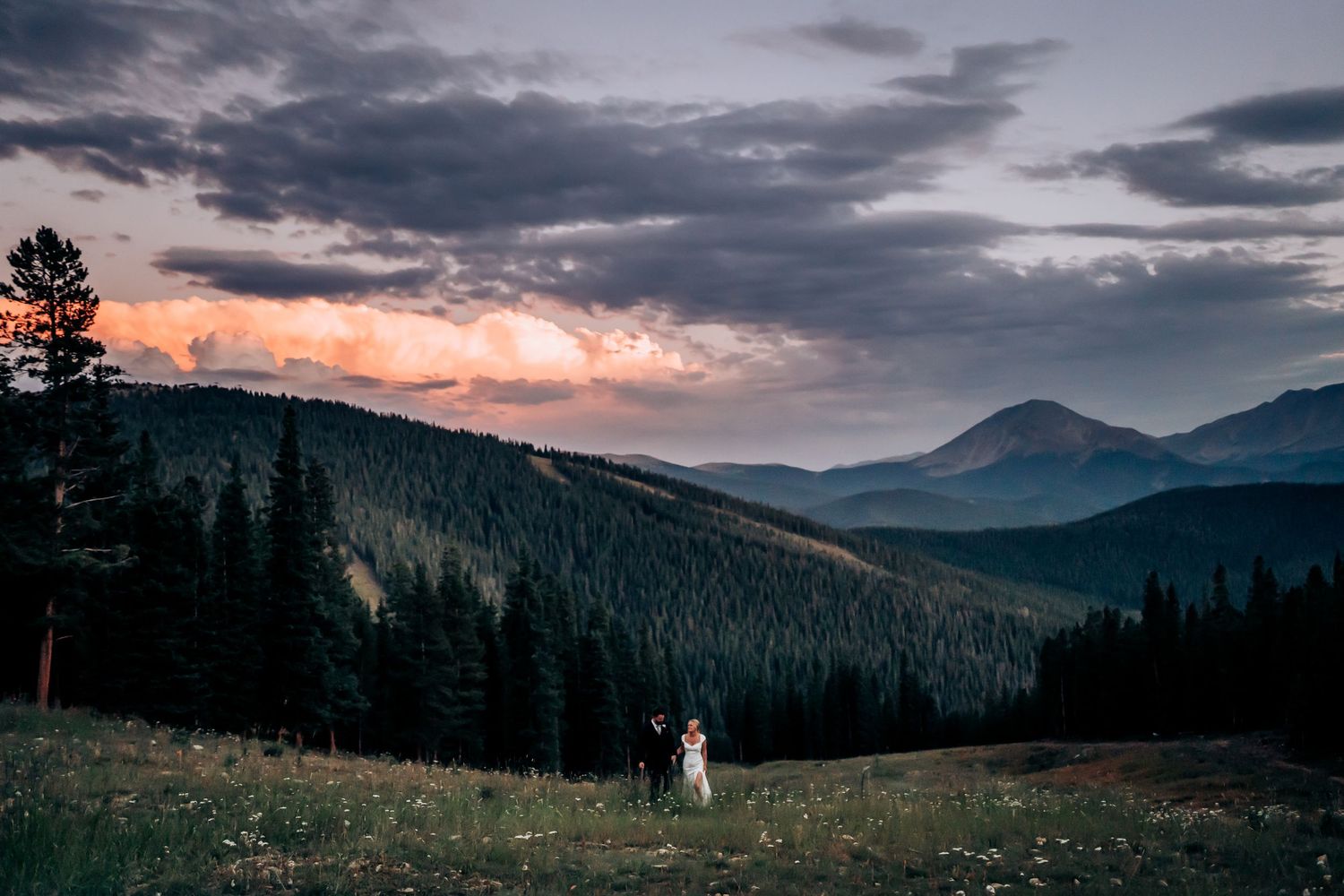 Dramatic mountain vista with stormy clouds and sunset colors over rugged peaks.