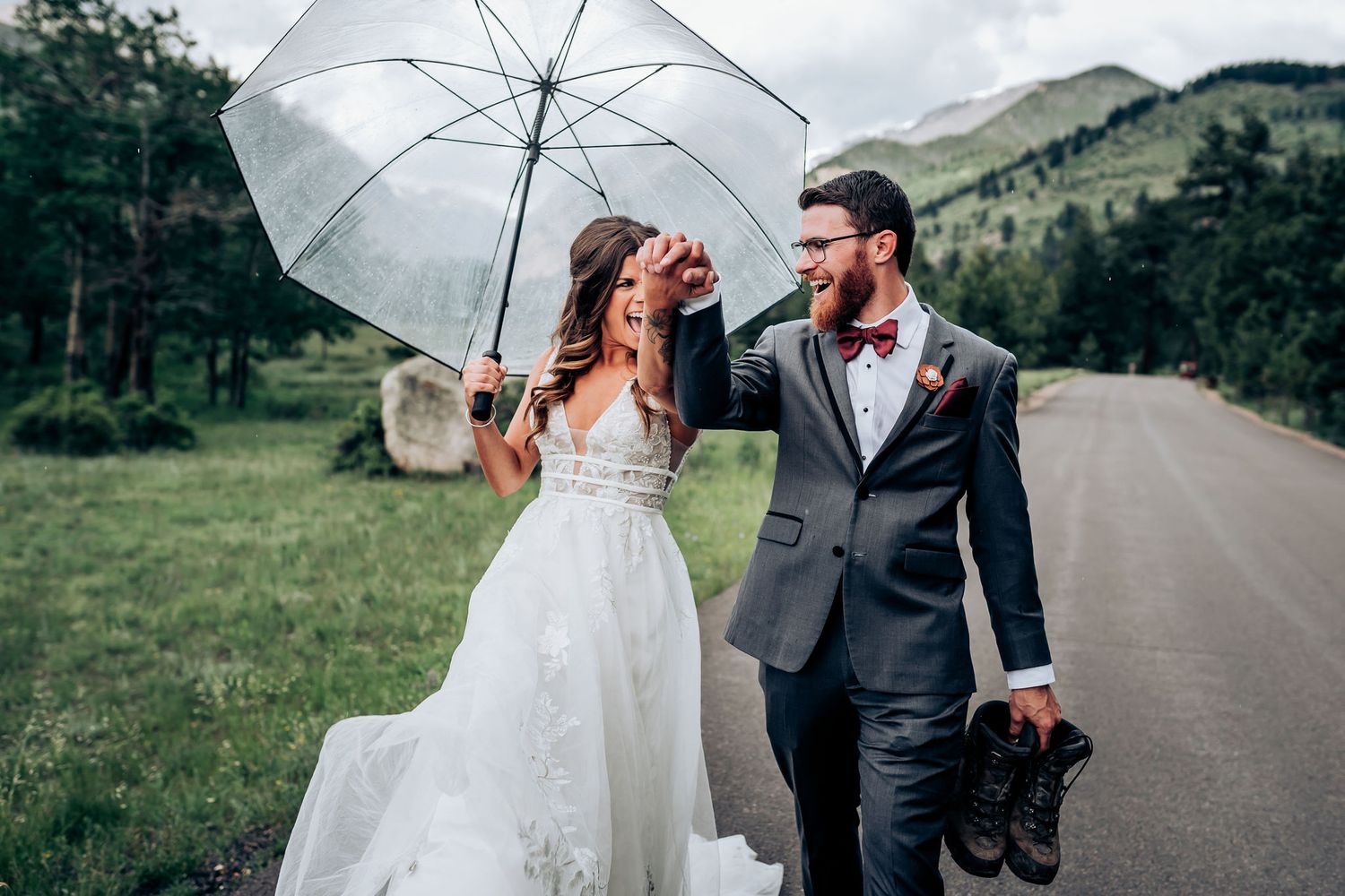 A romantic wedding photo on a mountain road with a white umbrella and lush green scenery.
