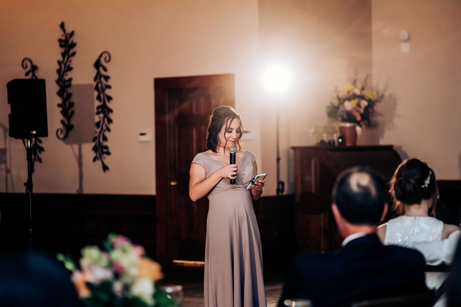 Wedding guest in mauve dress giving emotional speech during reception celebration.