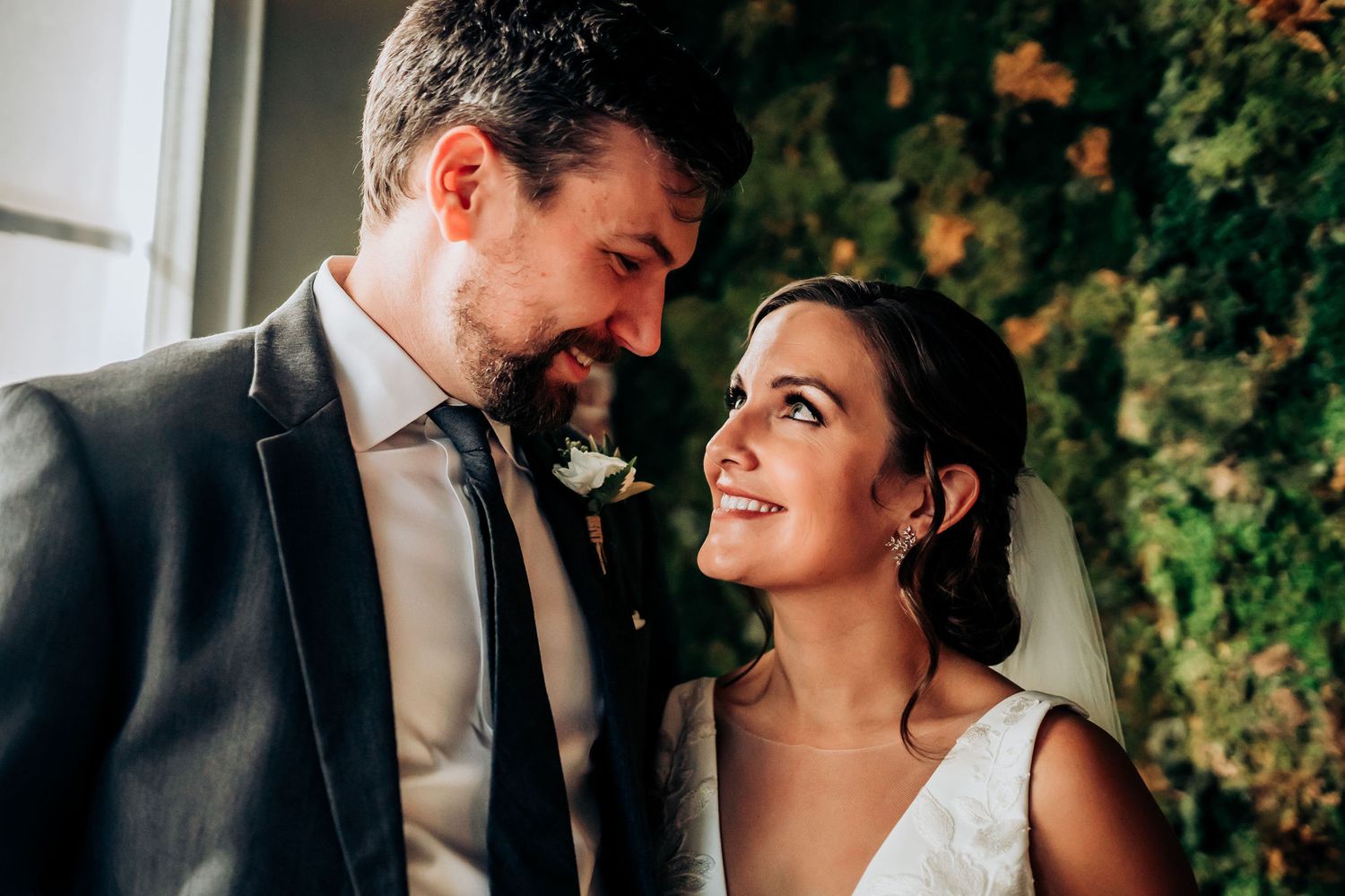 A joyful wedding couple sharing an intimate moment together against a backdrop of greenery.