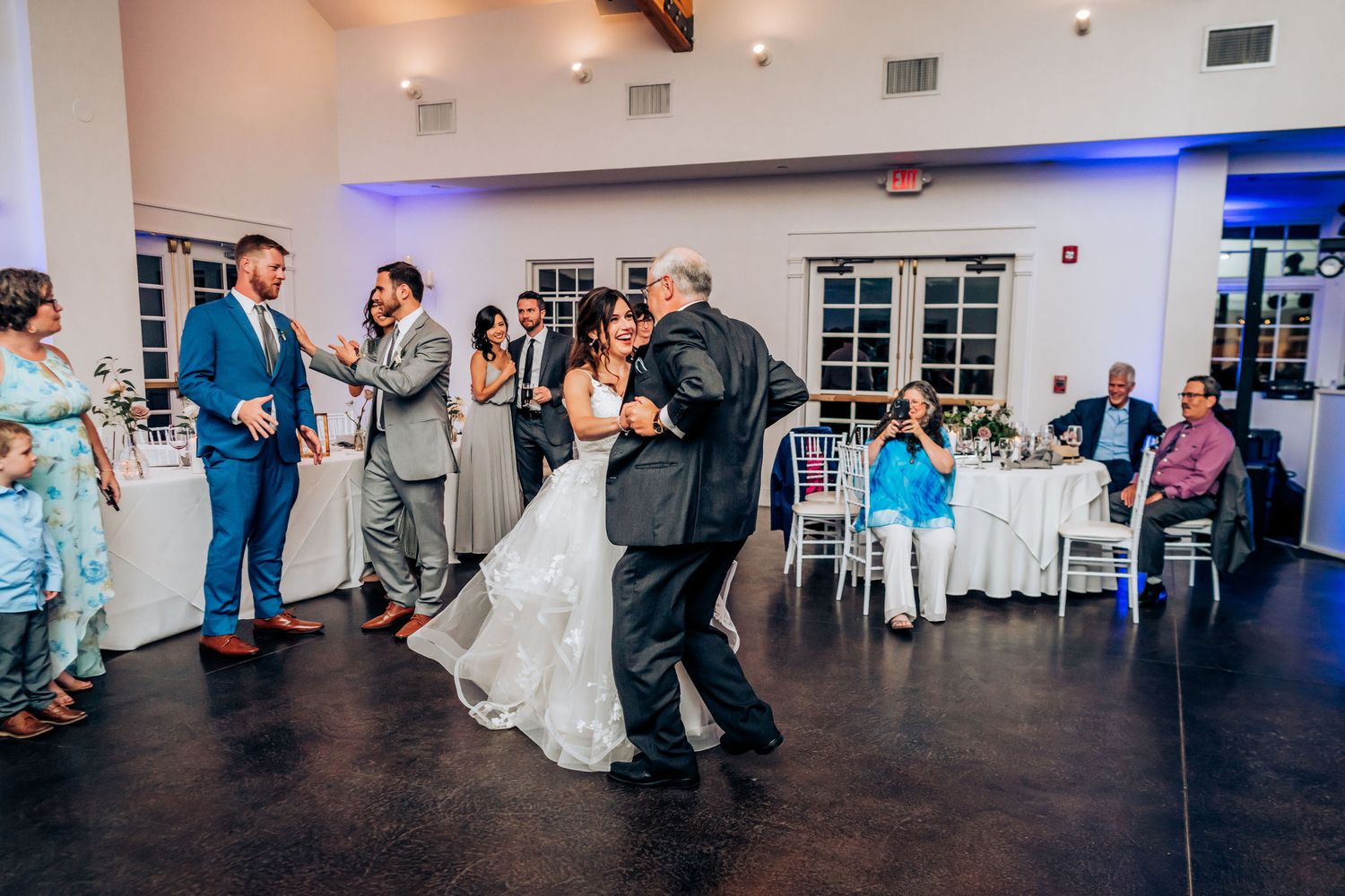 A couple shares an emotional first dance moment at their wedding reception while guests look on.