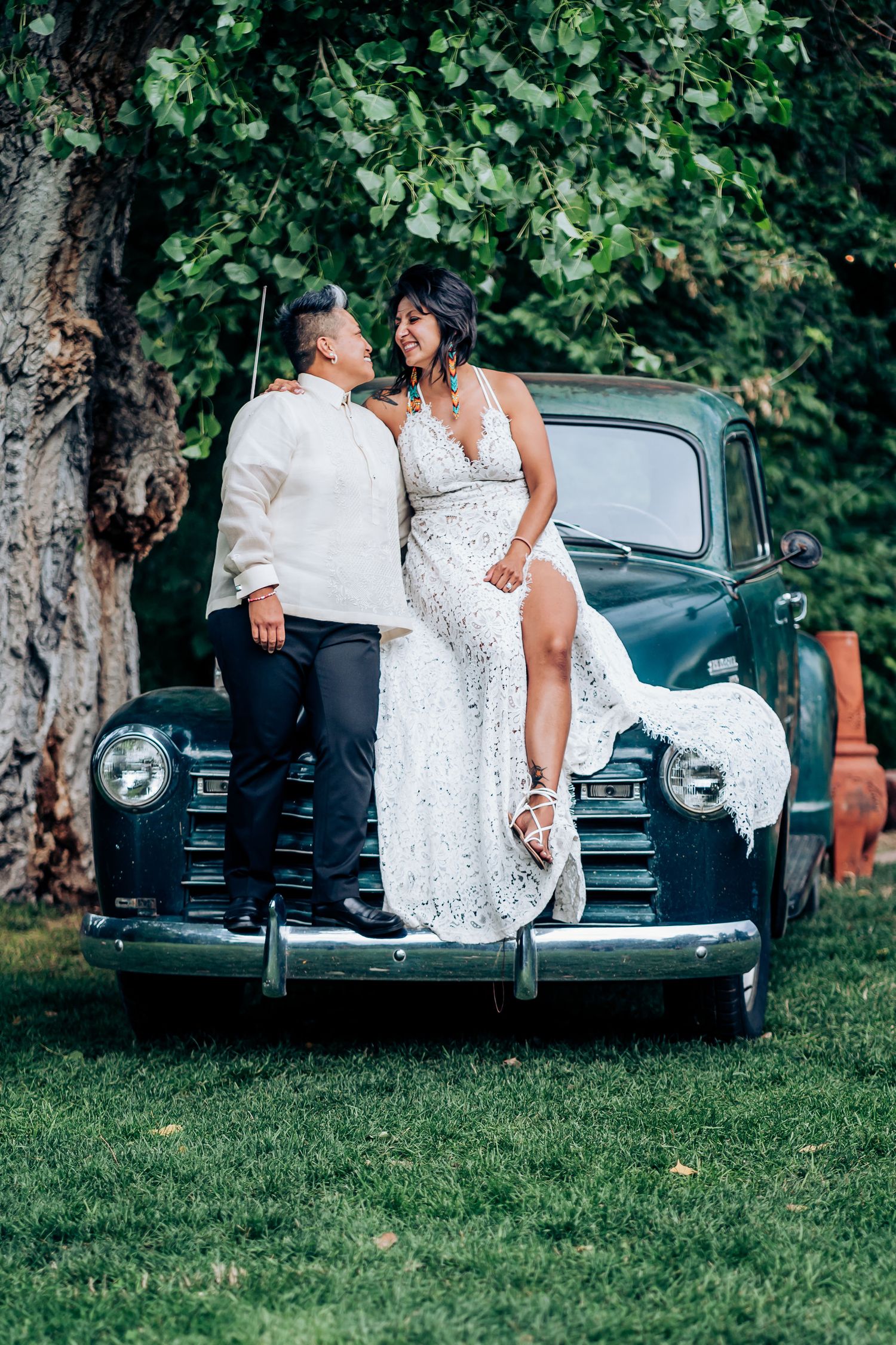 A classic vintage blue pickup truck serves as backdrop for a romantic wedding photo.