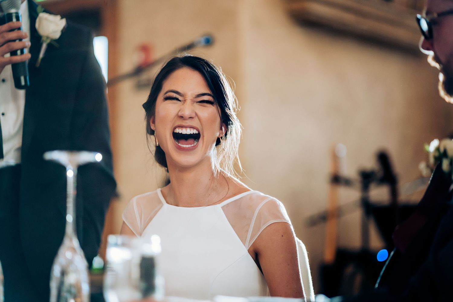 Happy bride laughing joyfully during wedding reception speeches.
