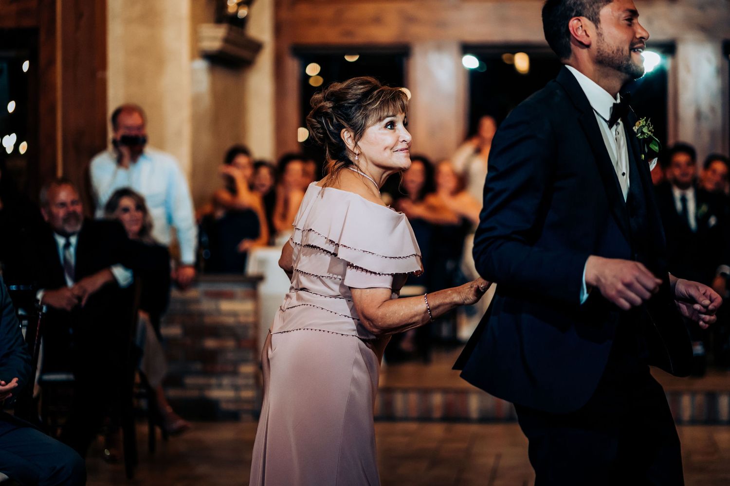 Guests dance and celebrate during a wedding reception in an elegant rustic venue.