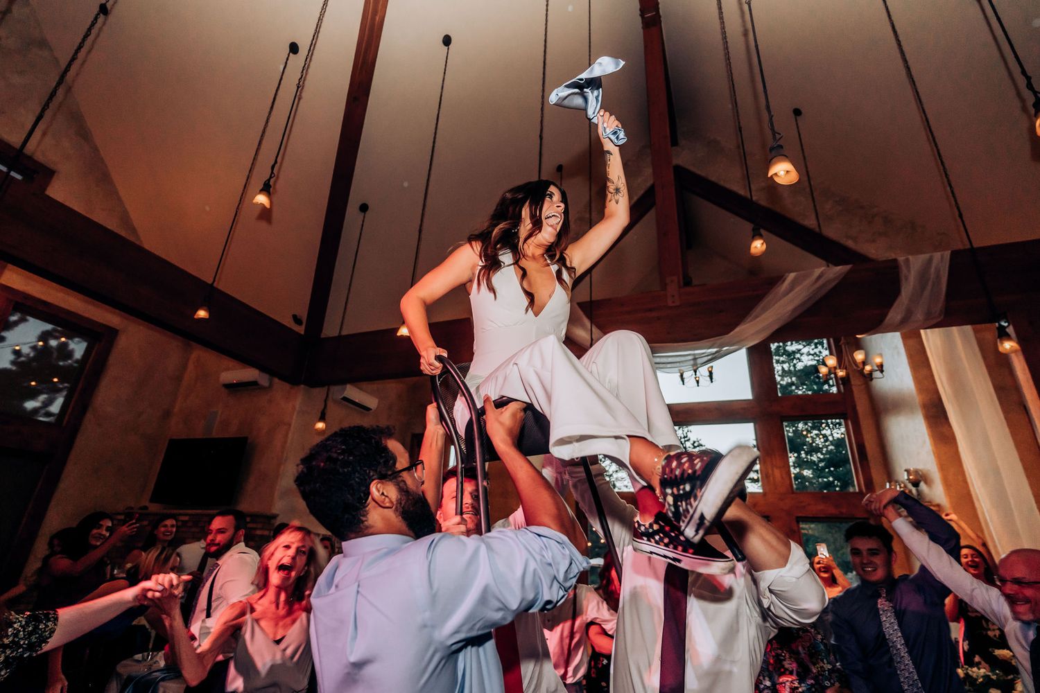 Wedding guests performing traditional celebration dance with people lifted on shoulders.