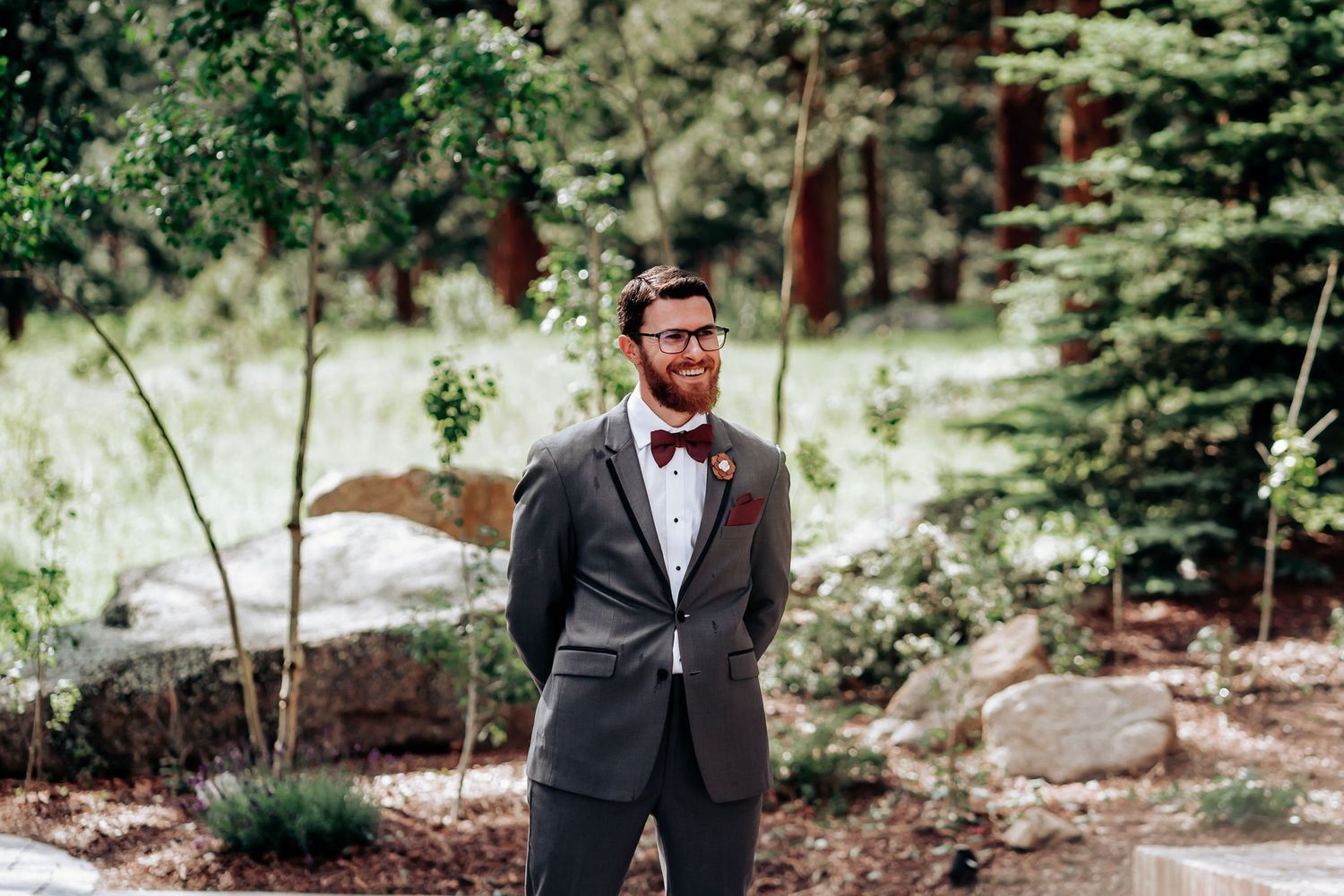 A suited figure stands thoughtfully in a serene forest garden setting.