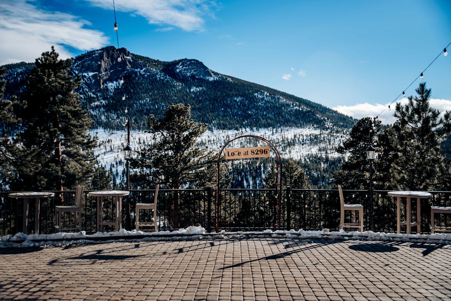 Snow-capped mountain vista with empty wooden deck chairs under blue winter sky.