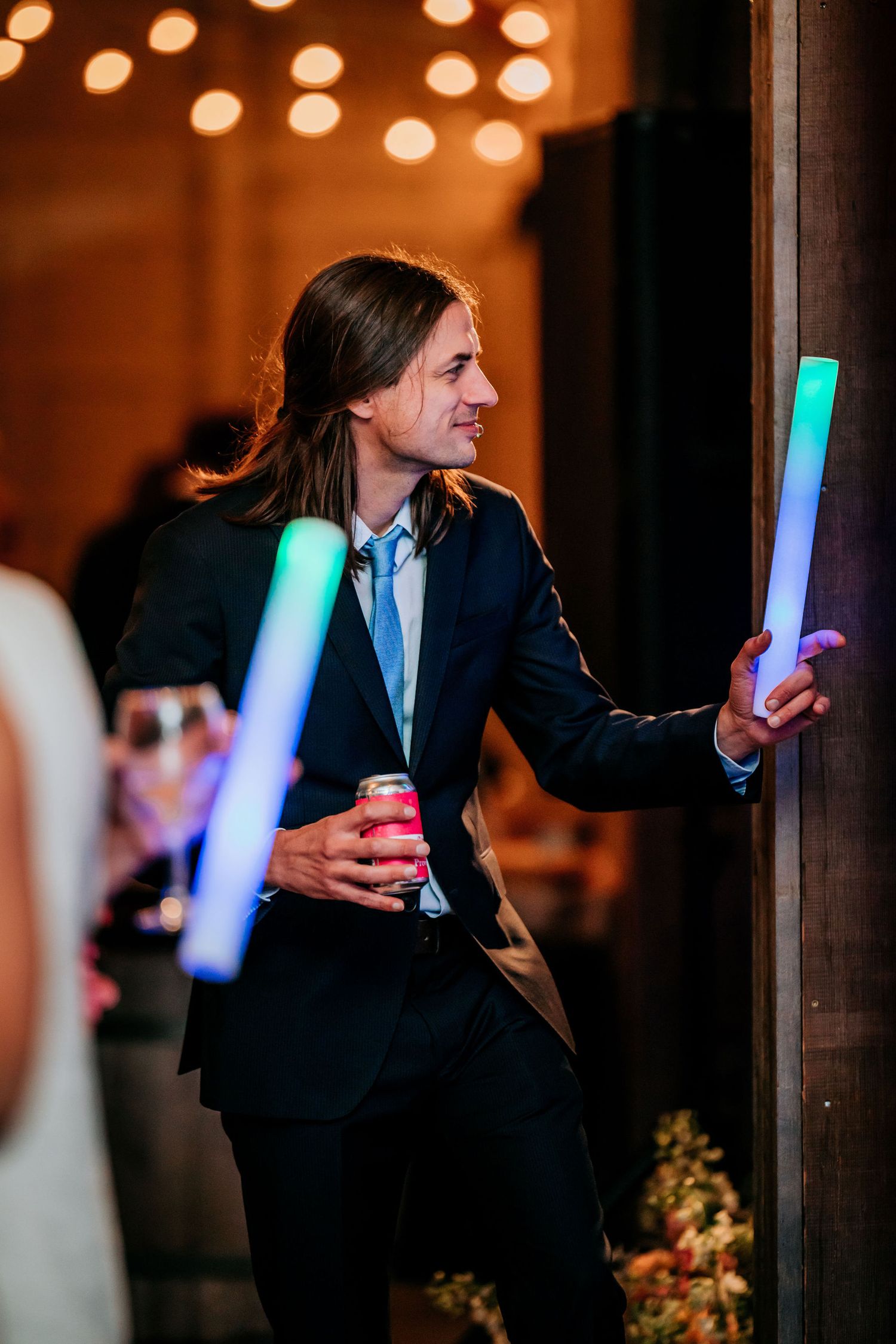 Party guest holds glowing LED light stick while celebrating at evening event.