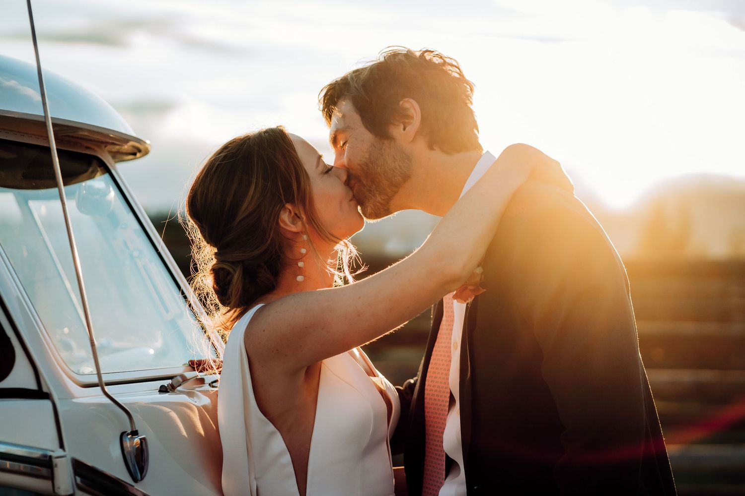 A romantic embrace captured during golden hour beside a classic Volkswagen bus.