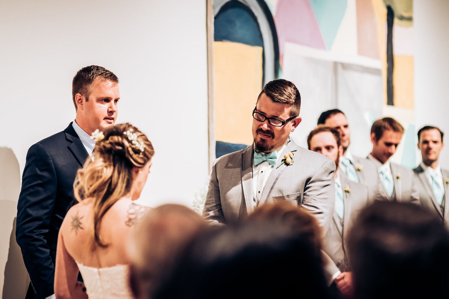 Intimate indoor wedding ceremony with attendees gathered in a modern art gallery setting.