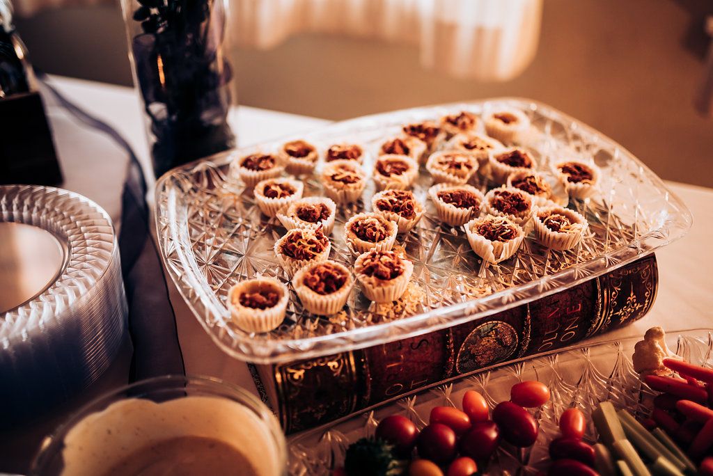 Crystal platter filled with fruit-topped pastry bites at an elegant event dessert table.