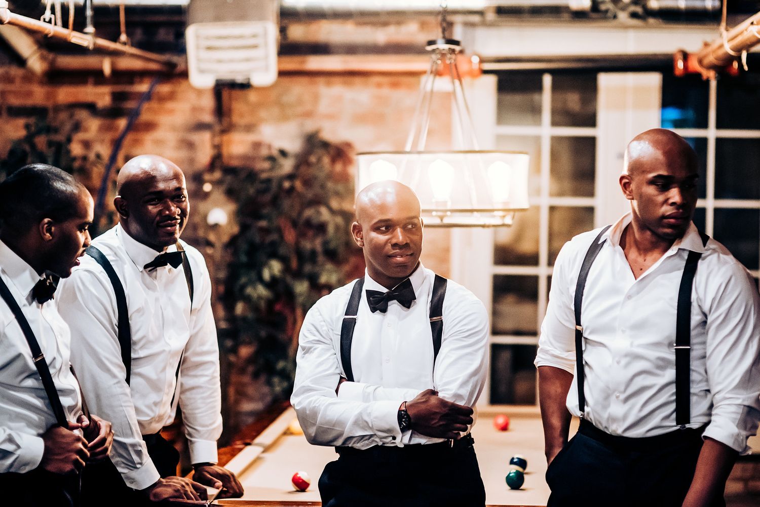 Groomsmen gather around a pool table during wedding celebrations.