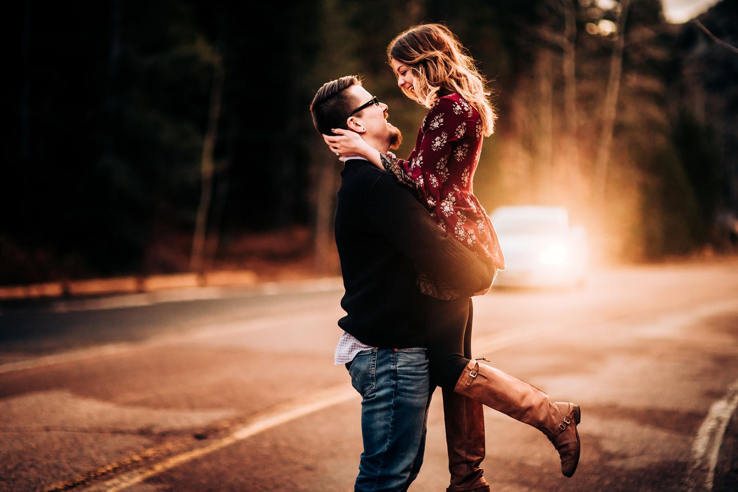 Romantic couple embracing on sunset-lit rural road.