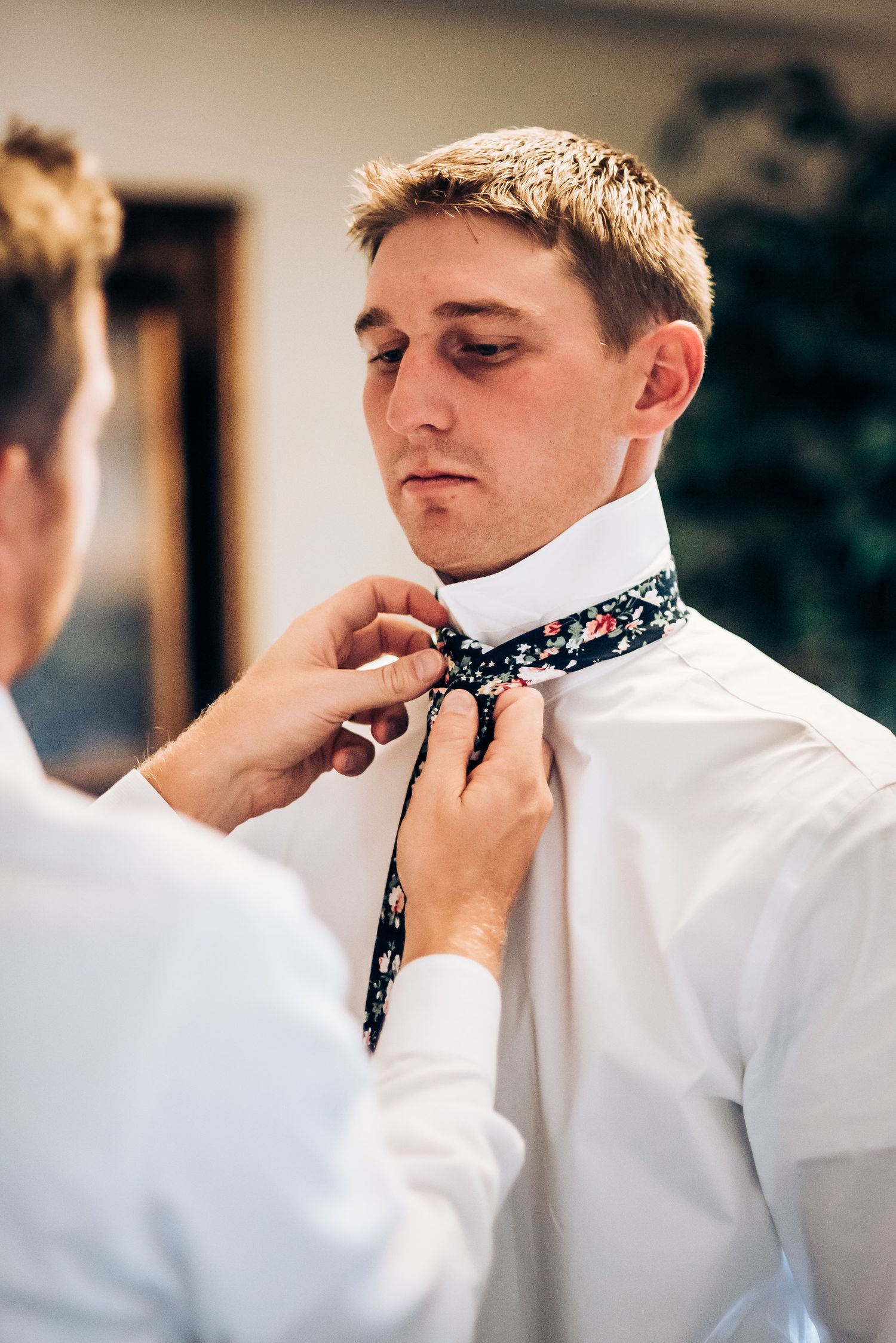 Detailed shot of adjusting floral patterned tie during preparation.