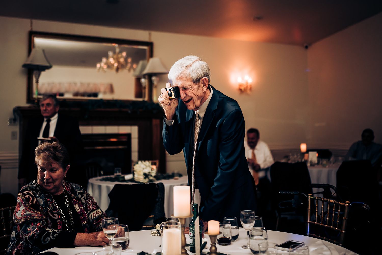 Guest gestures emotionally during formal dinner event with elegant table settings.
