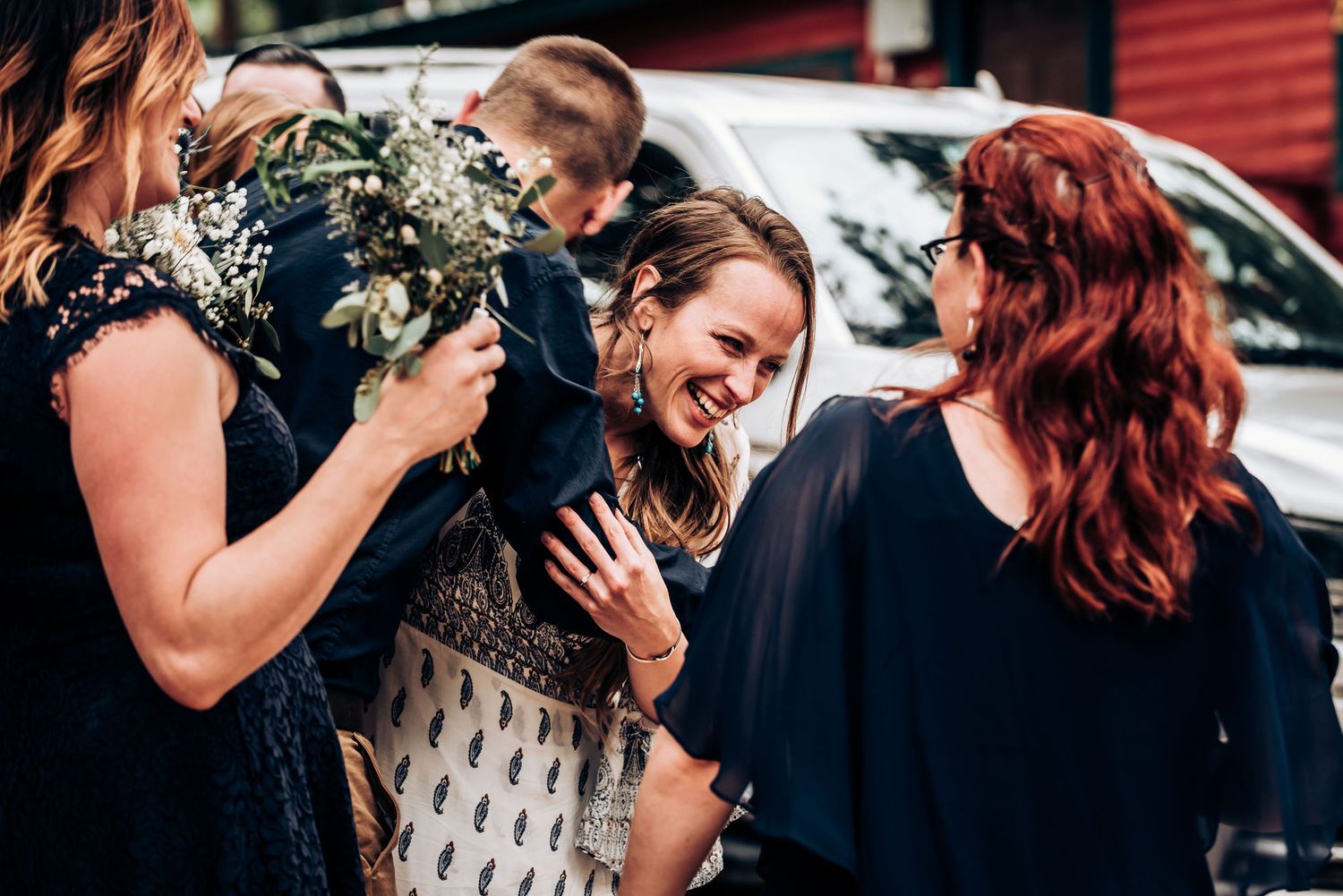 Friends share an emotional laugh while holding delicate white floral bouquets.