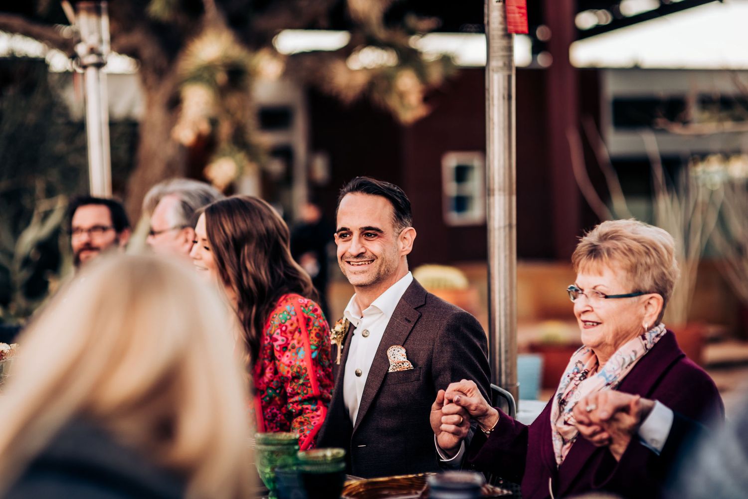 Guests enjoying outdoor dinner party with heater lamps and festive atmosphere.