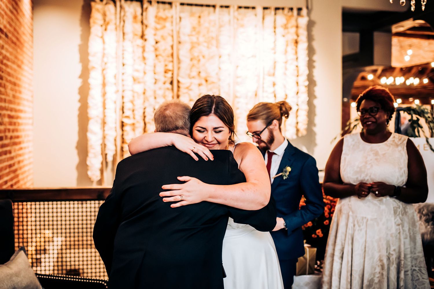 Emotional embrace during wedding ceremony with guests looking on in beautifully decorated venue.