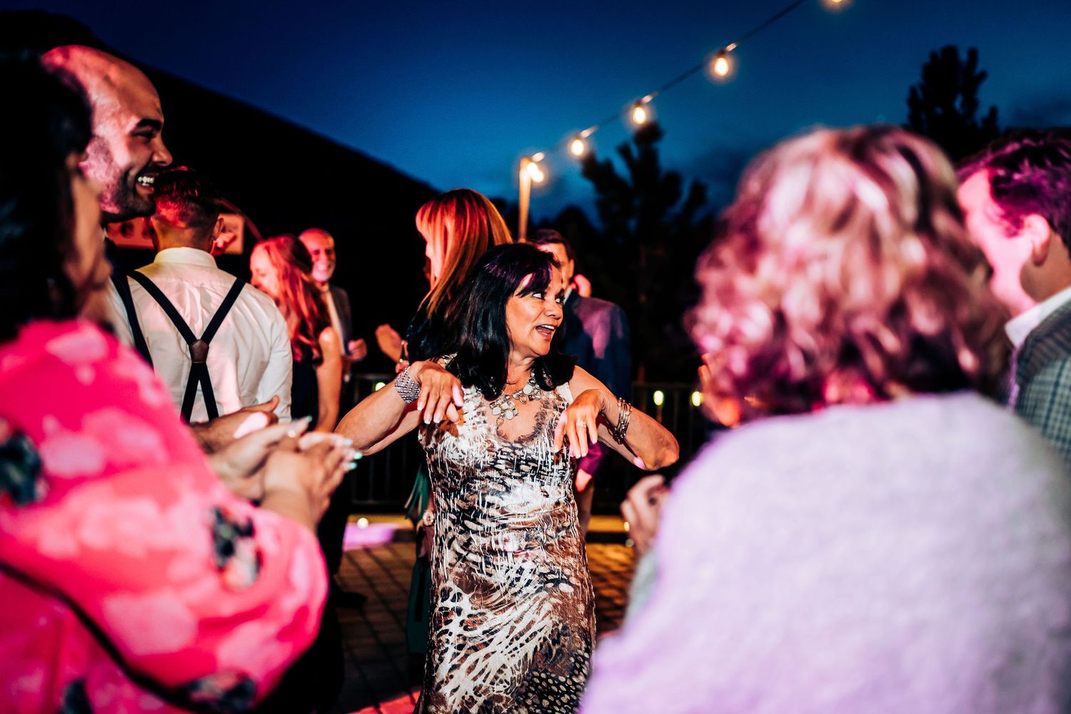 A festive wedding reception dance party with guests in formal attire.