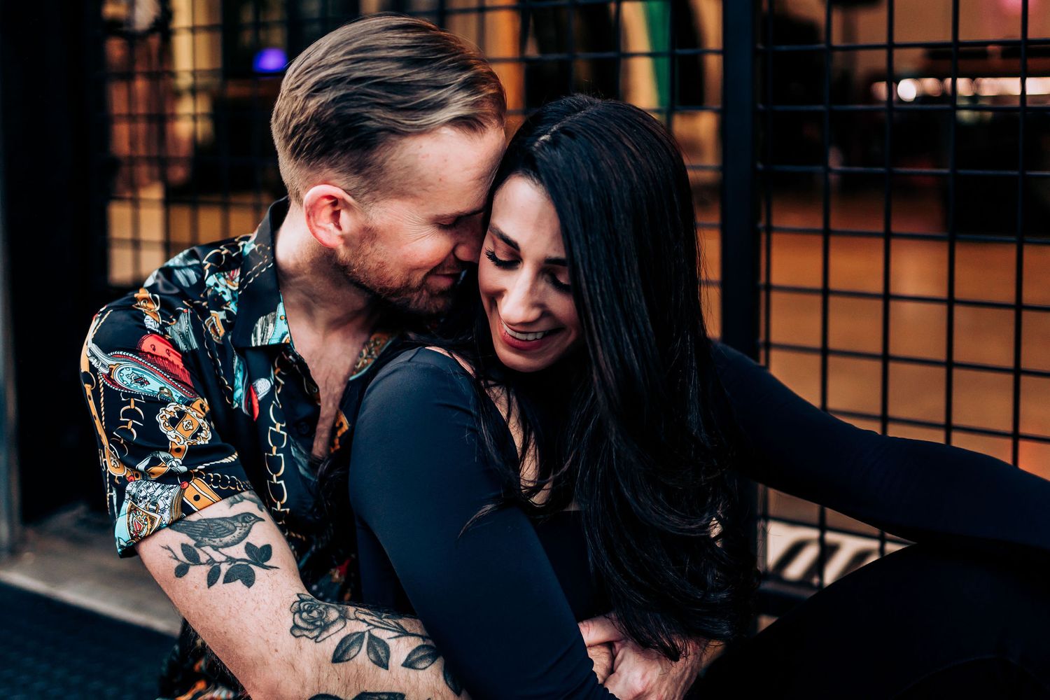 A couple shares an intimate moment while one wears a floral print shirt.