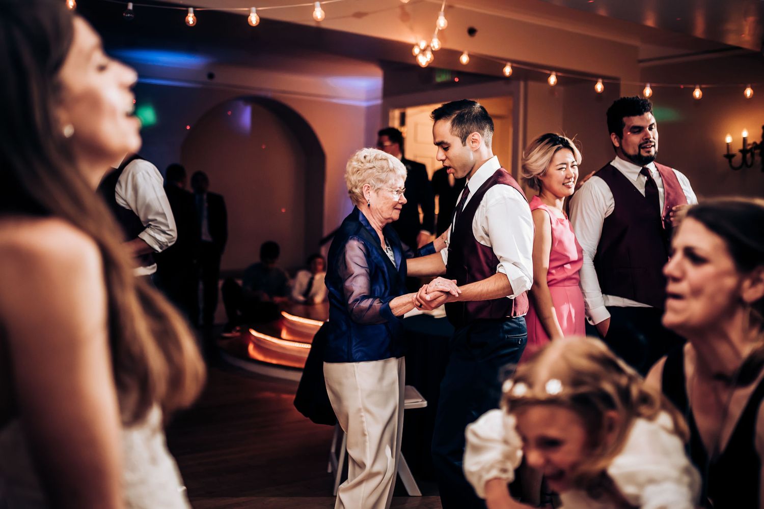 Wedding reception guests enjoying a dance in a beautifully lit ballroom.