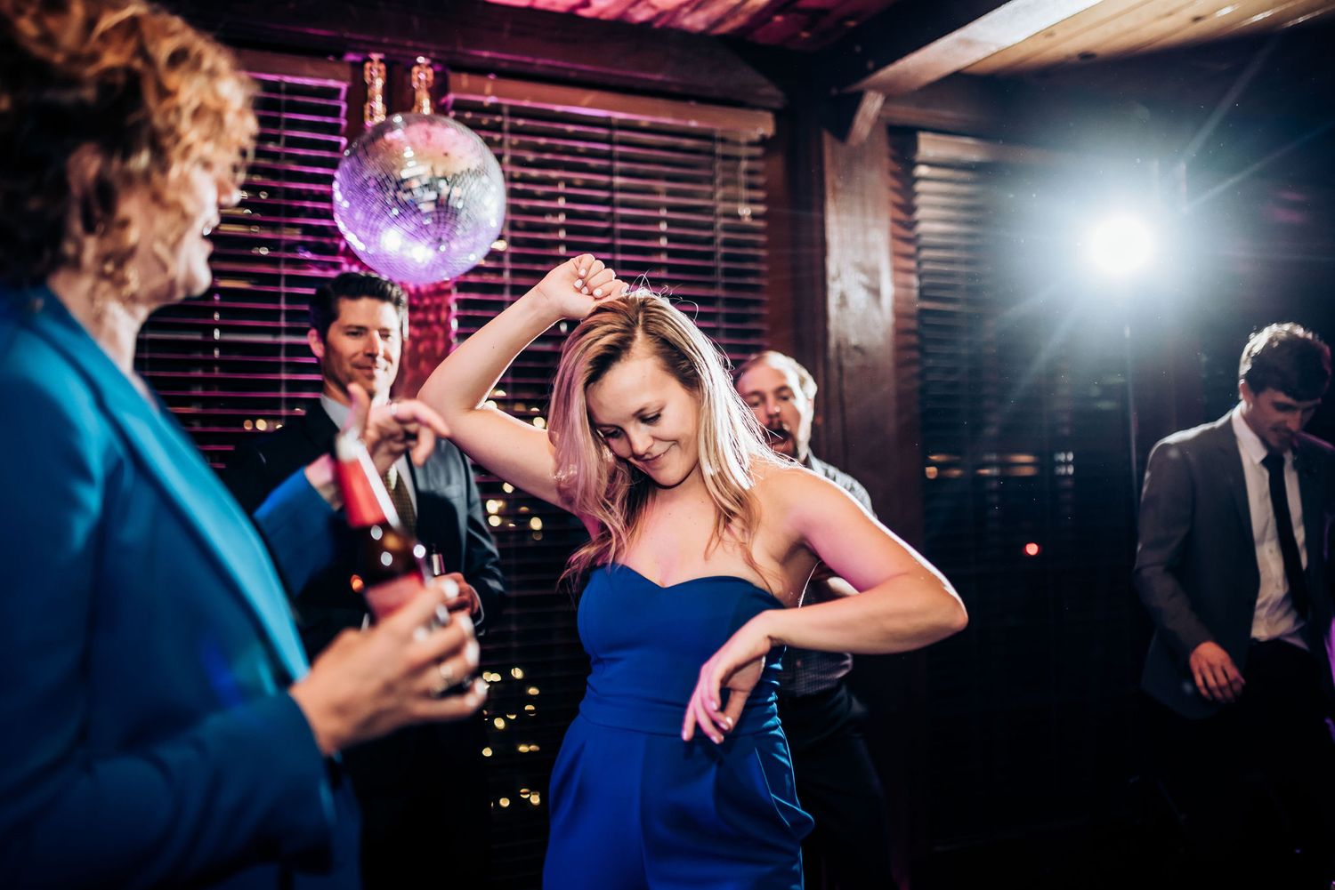 People dancing and celebrating under a disco ball at a nighttime party.