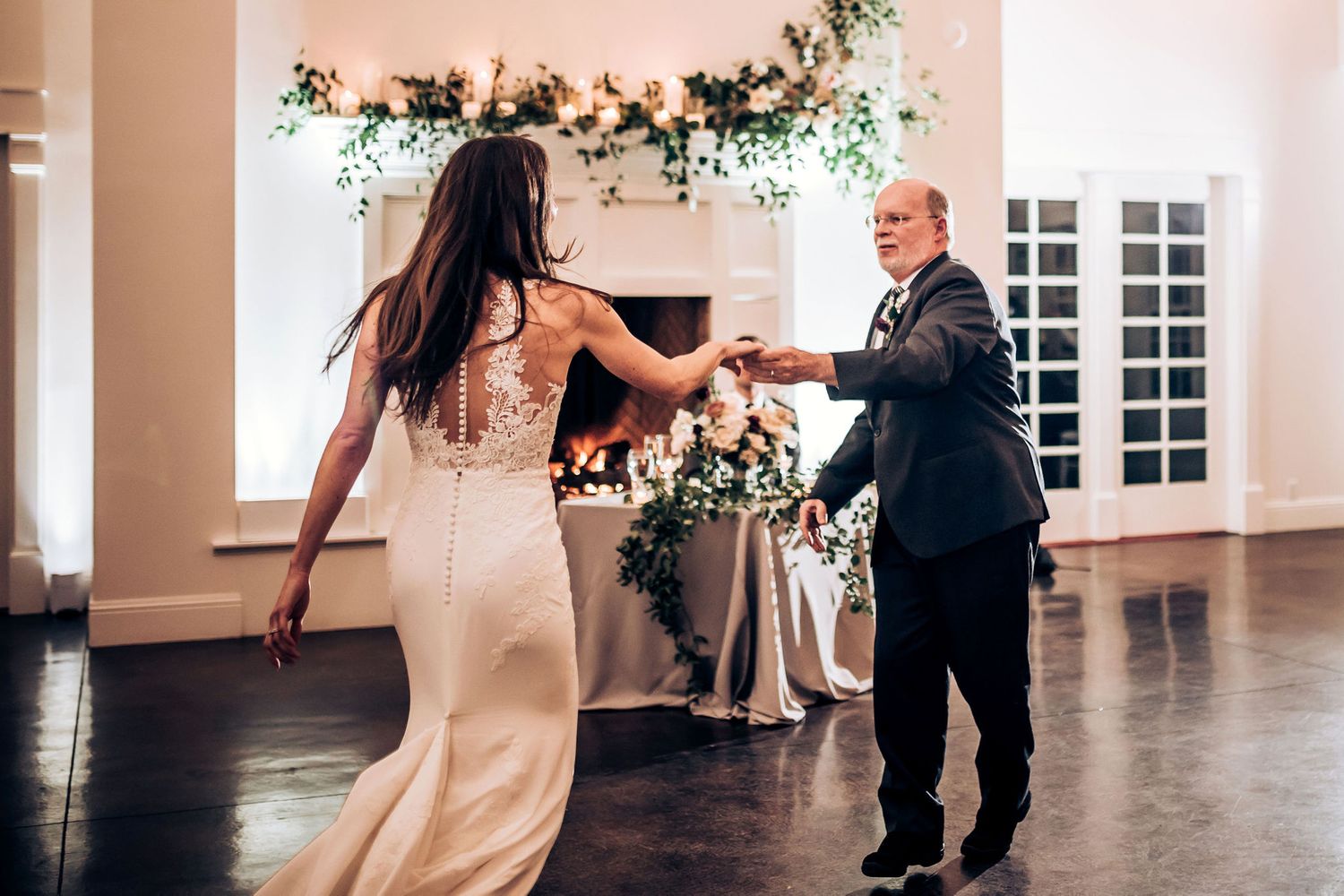 A playful dancing moment captured in an elegant reception venue with floral decor.