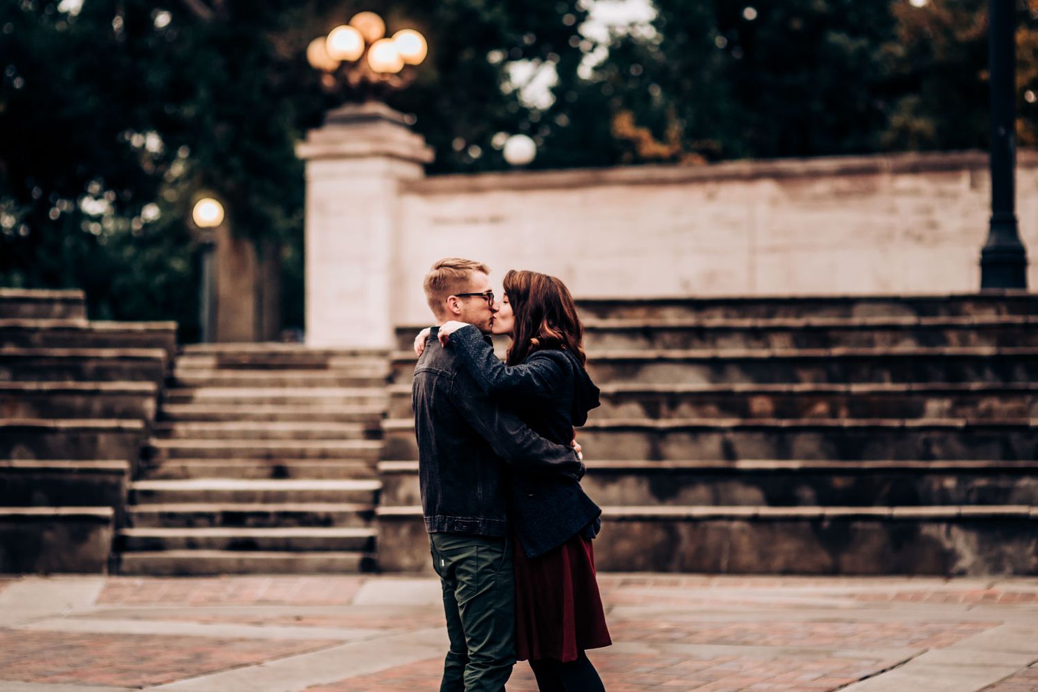 A tender moment shared between a couple on stone steps during a moody evening photoshoot.
