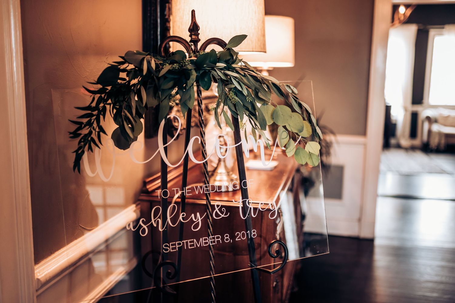 Wedding date displayed on glass with decorative greenery and soft lighting.