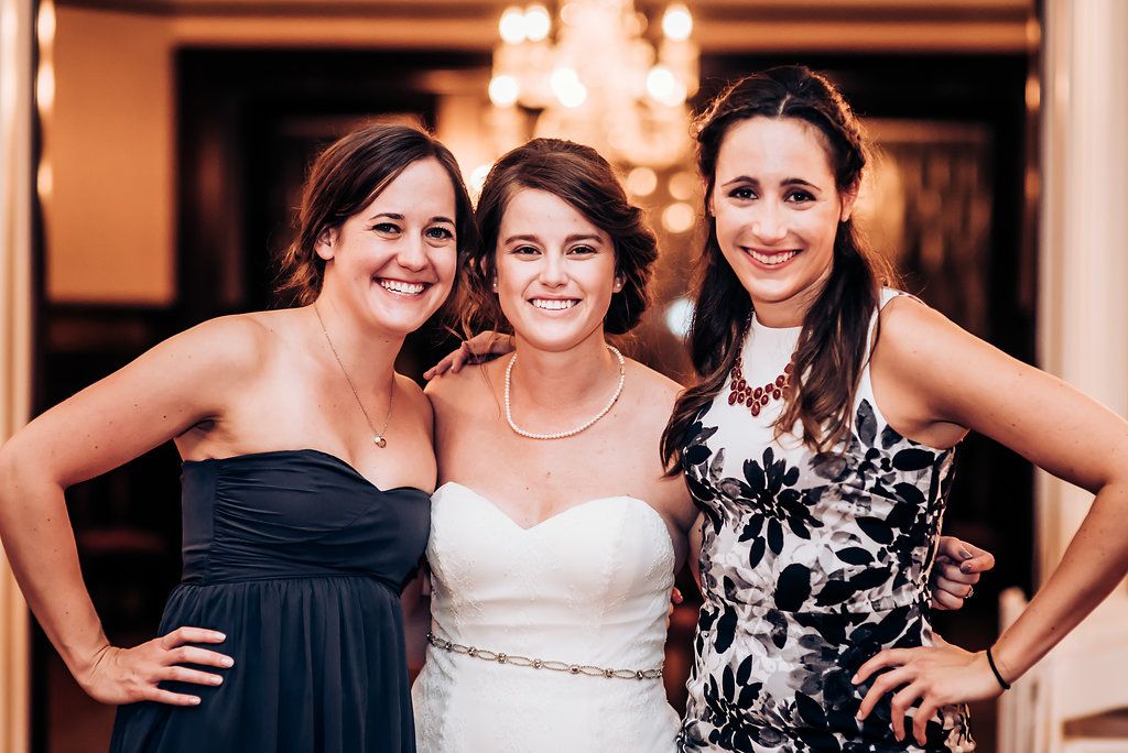 Three women in formal dresses posing together at an evening celebration.