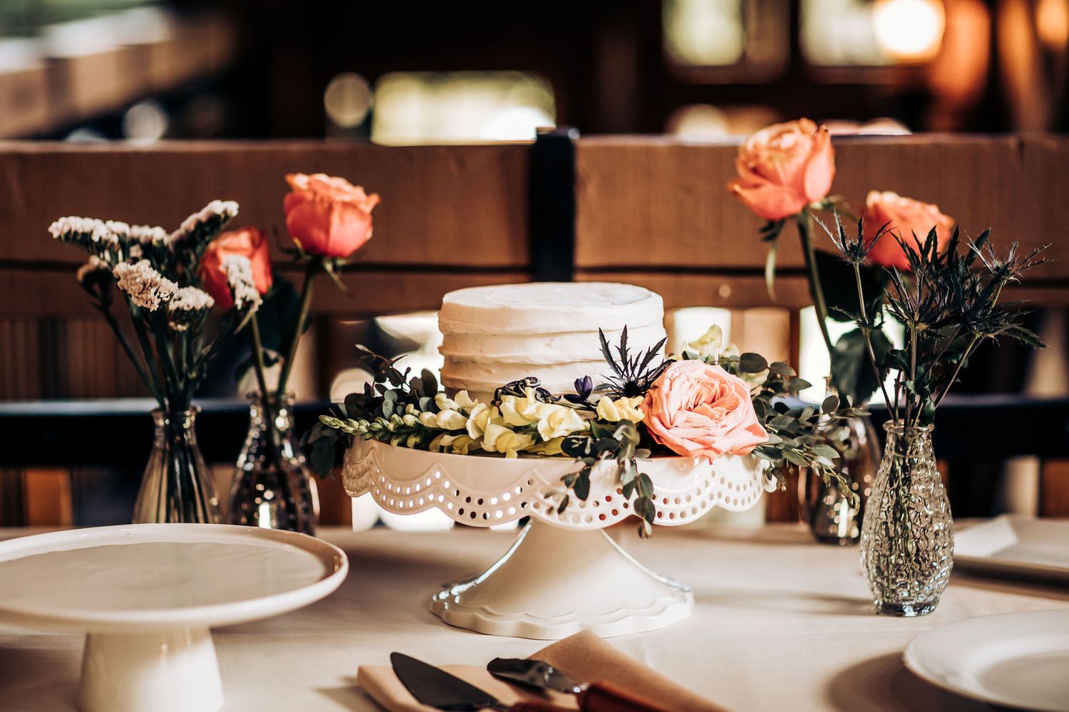 Elegant table setting with pink roses and white cake centerpiece.