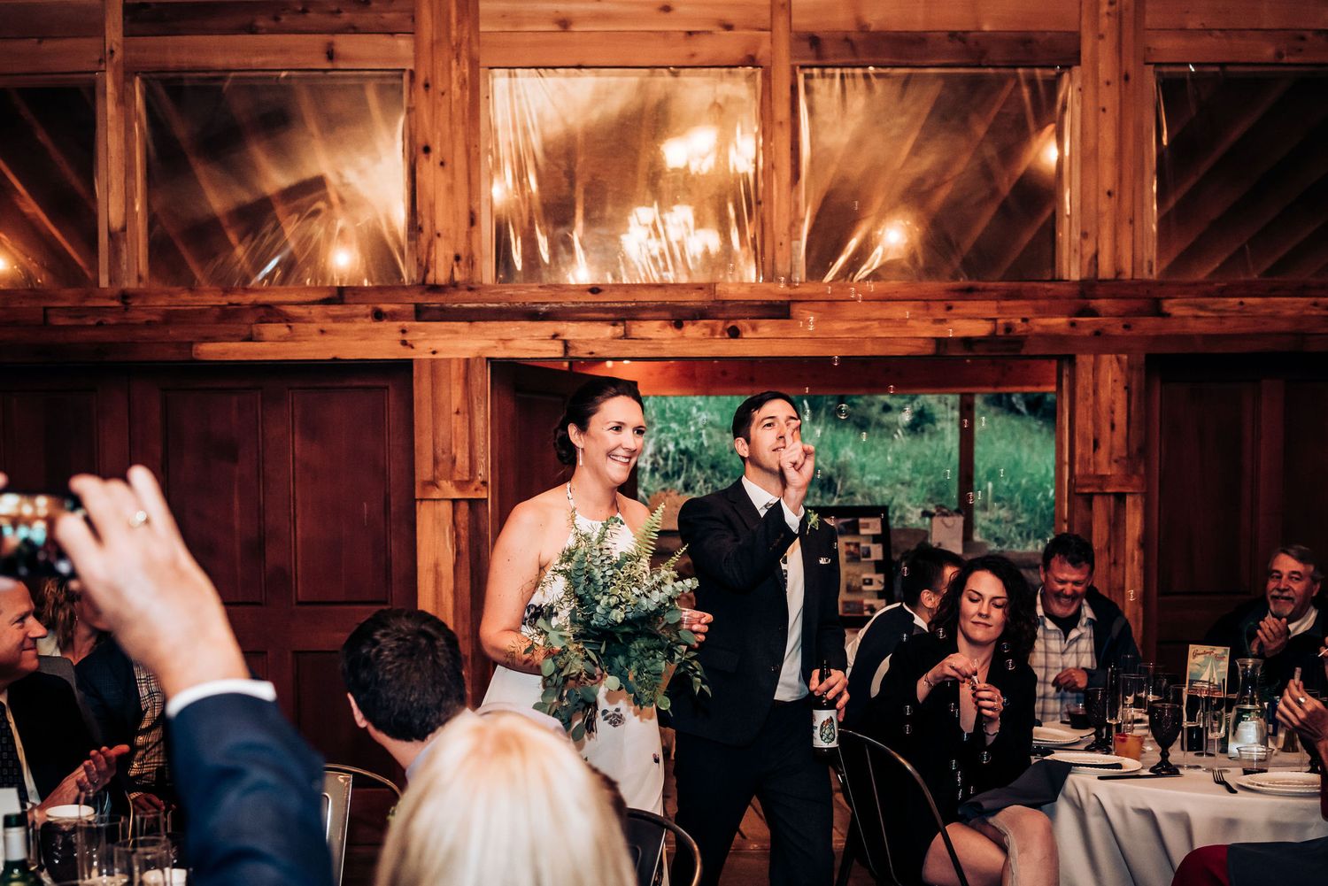Wedding celebration toast in rustic wooden barn with warm ambient lighting.