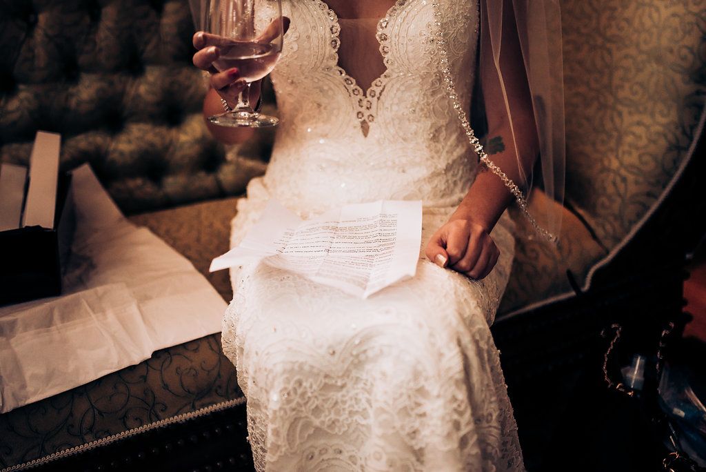 Detail shot of a lace wedding dress with papers being held.
