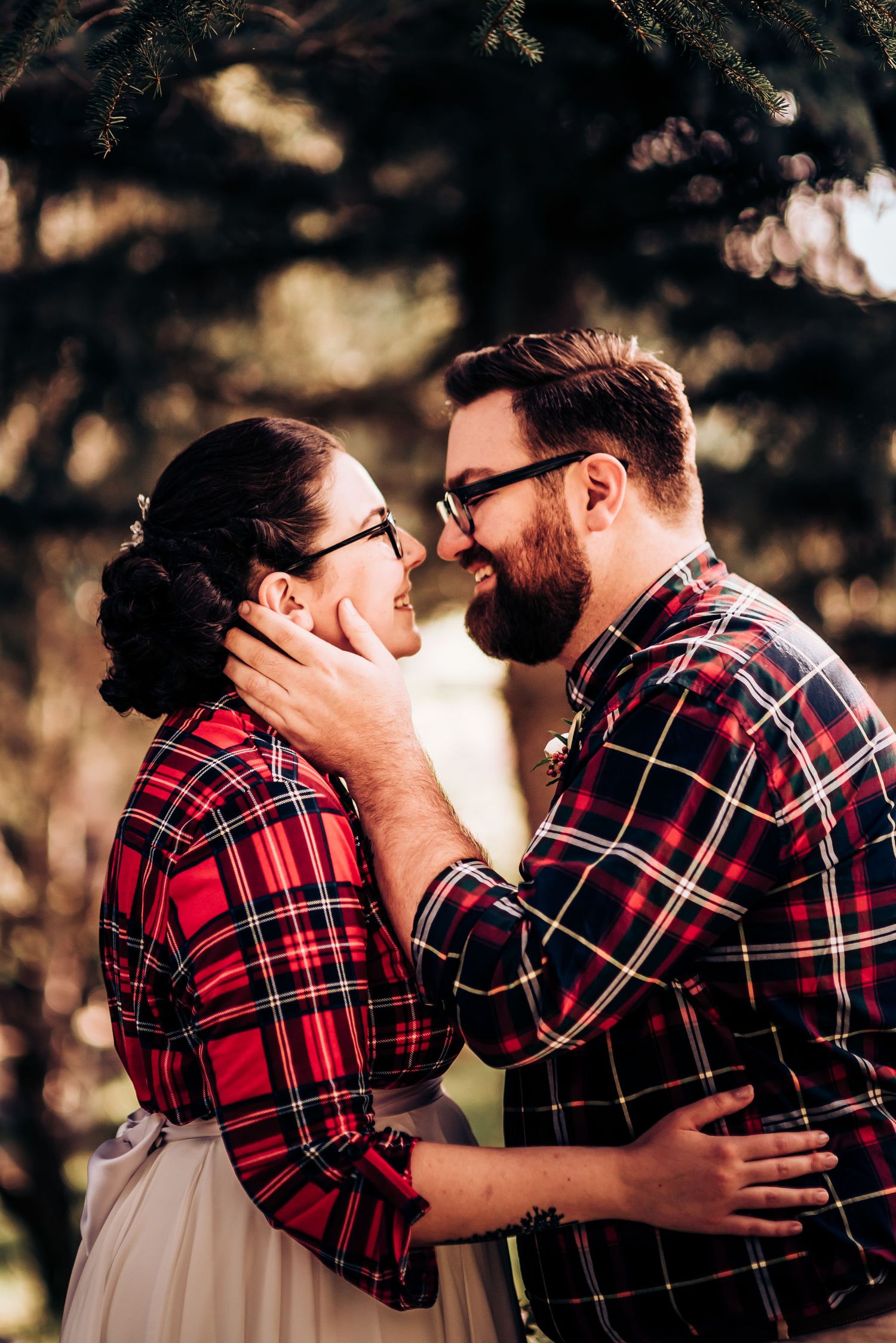 A tender romantic moment captured between a couple in matching plaid shirts during their outdoor shoot.