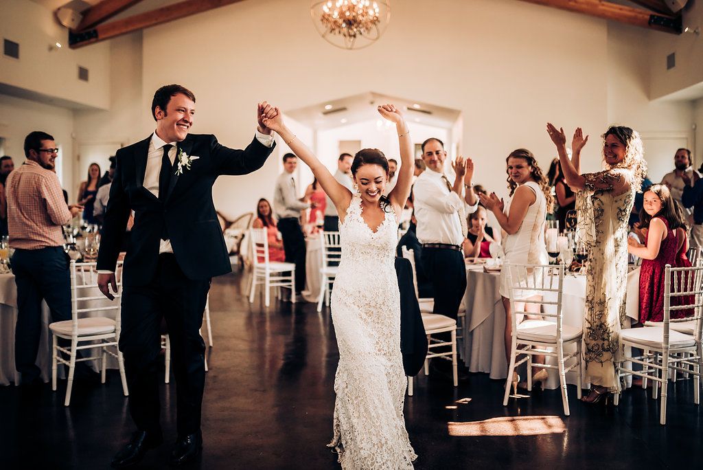 Celebration in a bright reception hall with guests dancing and cheering.
