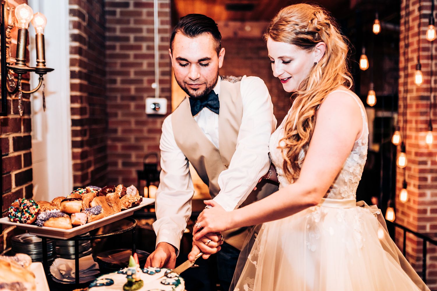 Newlyweds serve food together at their rustic brick venue wedding reception.