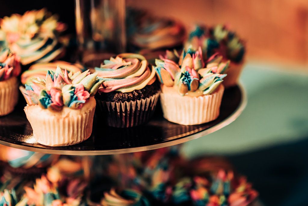 Beautifully decorated cupcakes with swirled frosting and colorful decorations displayed on a serving platter.