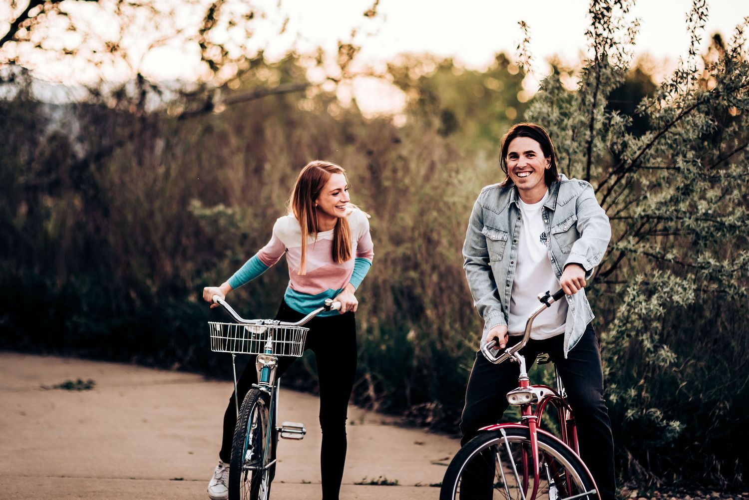 Two cyclists enjoying a casual bike ride on a paved path at sunset.