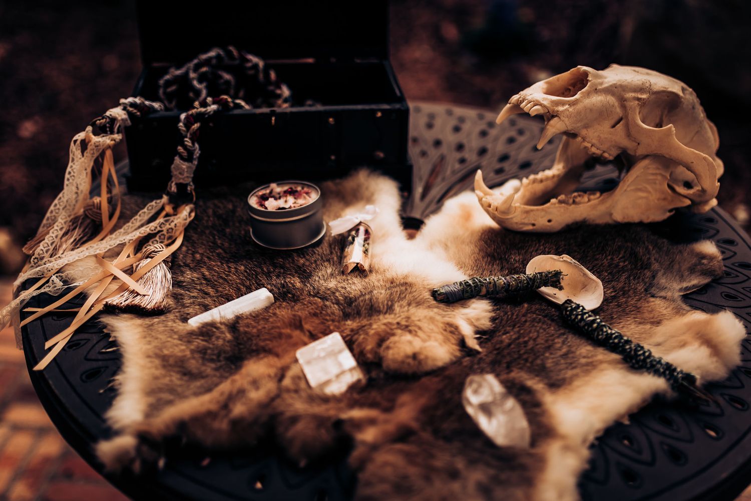 Animal skulls and fur arranged with ritual objects on a dark textured surface.
