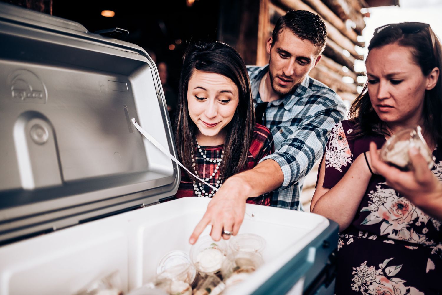 People looking into an ice chest filled with food at a casual outdoor gathering.