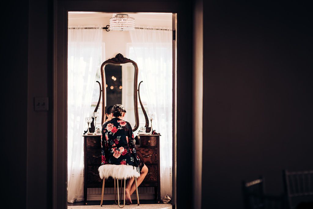 Silhouette at vintage vanity mirror in dramatic lighting.