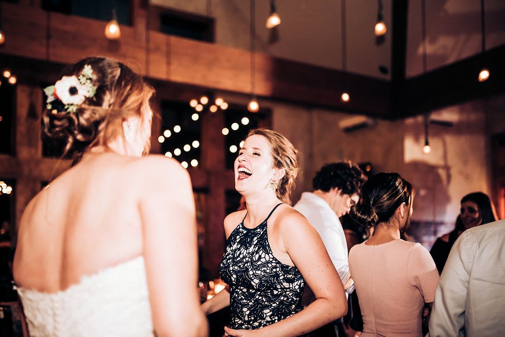 Joyful celebration moment captured at indoor wedding reception with string lights.