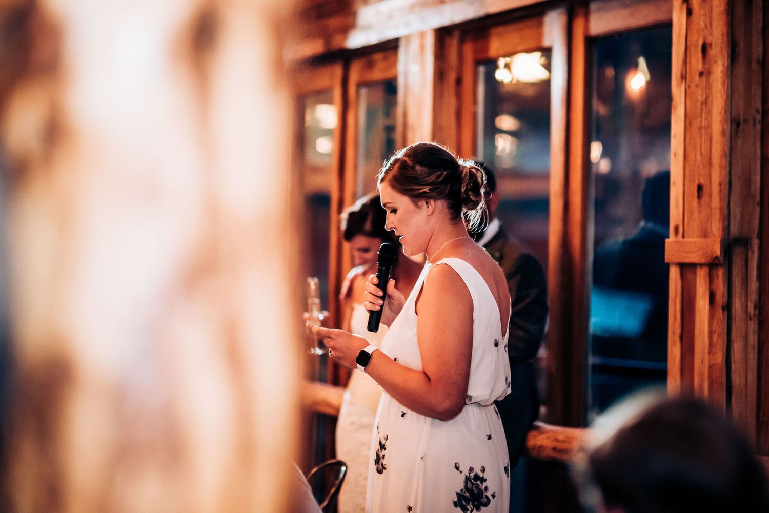 Guest gives speech at wooden lodge venue during evening celebration.
