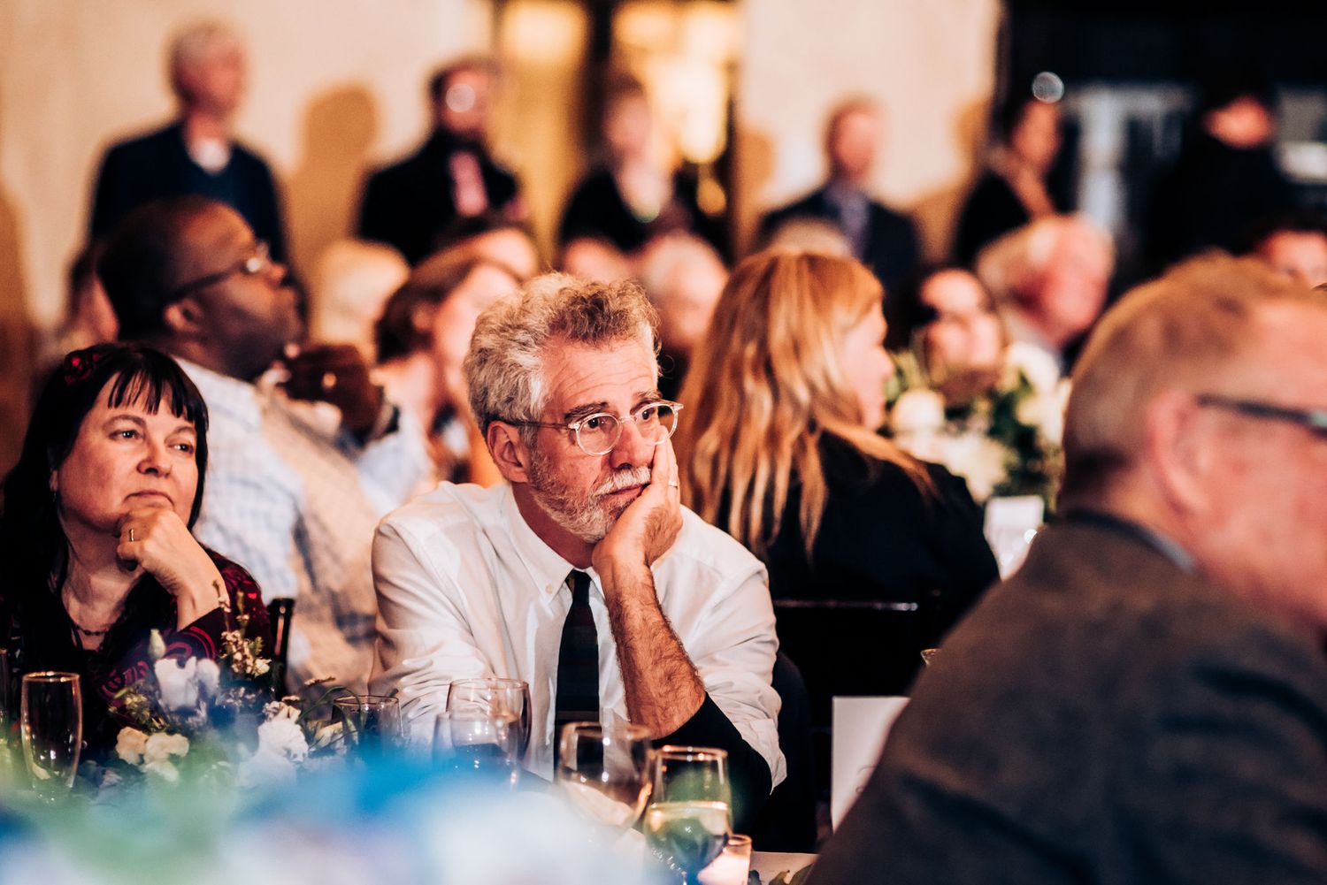 Guests seated at elegantly decorated dining tables during an indoor wedding reception.