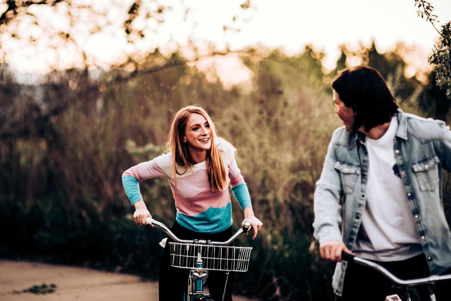 A couple shares a joyful bike ride together on a sunset path through nature.