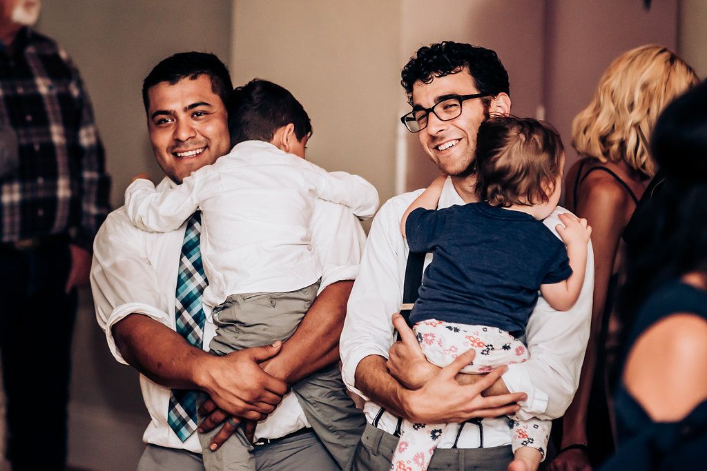 Guests holding children while socializing at an indoor celebration event.