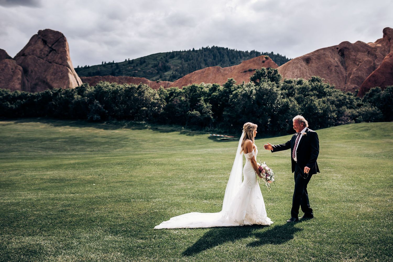 Newlyweds pose in scenic mountain landscape with dramatic rock formations.