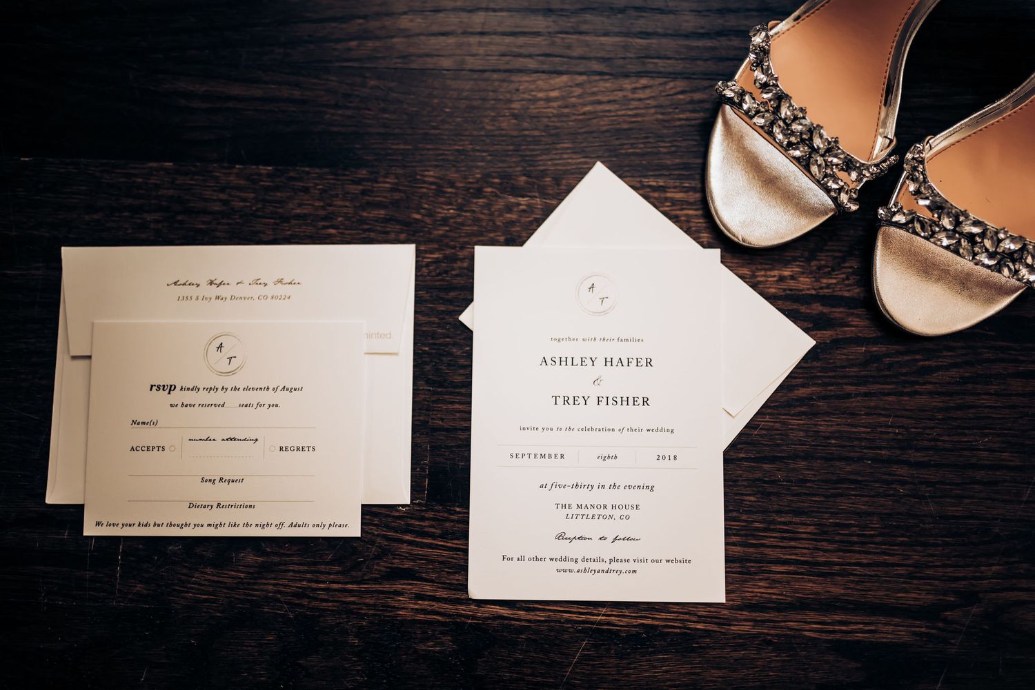 Wedding invitations and ornate bridal shoes arranged on dark wooden surface.